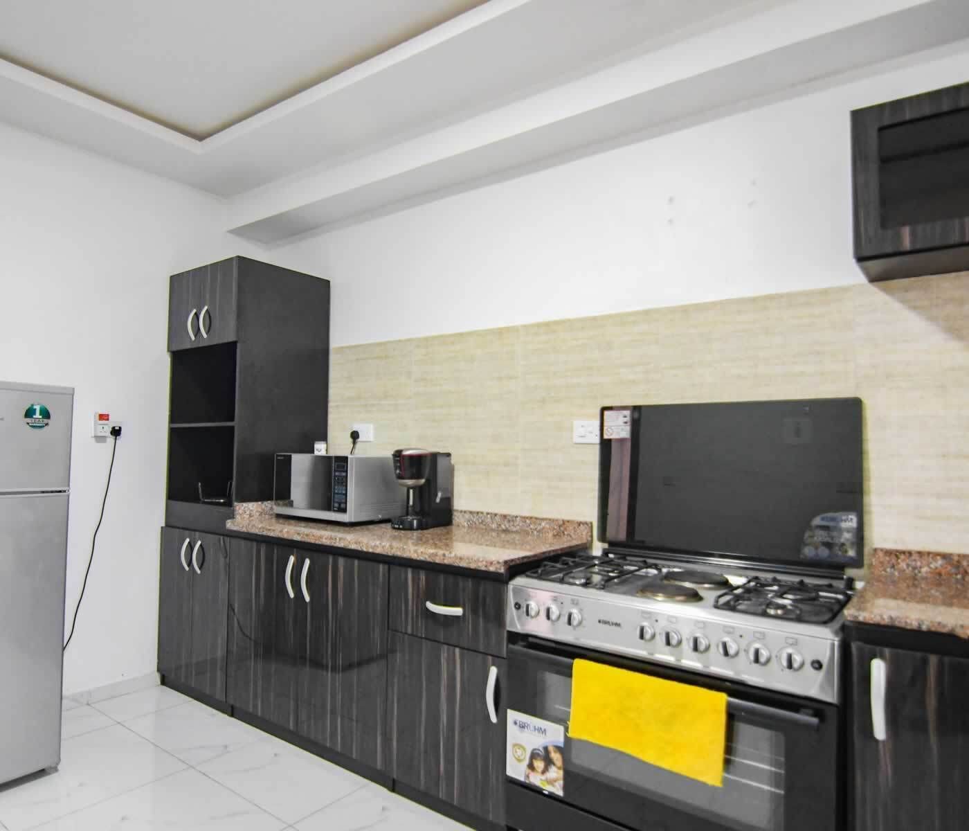 A kitchen with dark cabinets, a gas stove, a microwave, and a coffee maker.