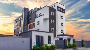 Un edificio moderno de varios pisos con techo plano, ventanas amplias y entrada protegida por una puerta.