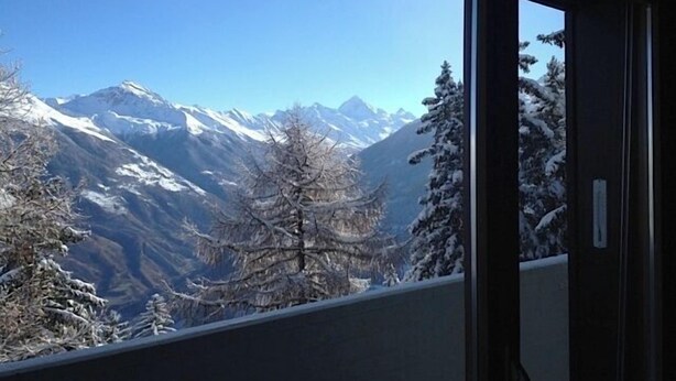 A mountain view through a window, featuring snow-covered peaks and trees. - Nice apartment for rent in les Collons (Thyon-Les Collons)