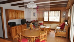 A cozy wooden interior with a dining area, a kitchen with wooden cabinets, and a window with curtains. - Nice renoveted flat for rent in Les Collons (Thyon-Les Collons)