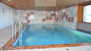 An indoor swimming pool with a tiled floor and walls, a wooden ceiling, and a logo on the wall. - Nice renoveted flat for rent in Les Collons (Thyon-Les Collons)