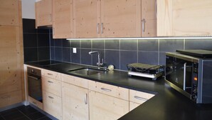 Una cocina moderna con armarios de madera, encimera negra, horno integrado y microondas.