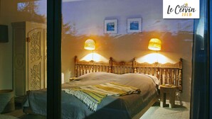 A bedroom with a wooden bed, two wall-mounted lamps, and a small nightstand. - Apartment for rent in les Collons (Thyon-Les Collons)