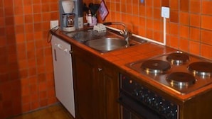 Una cocina compacta con armarios de madera, horno empotrado, cocina y cafetera.