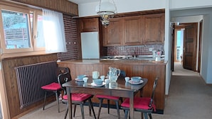 A kitchen with wooden cabinets, a dining table with chairs, and a radiator.