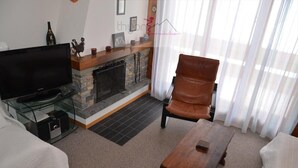A living room with a flat-screen TV, a fireplace, a leather armchair, and a wooden coffee table. - The Le Panorama building is located on the 1800 level of the Collons resort. Ideally located, it is (Thyon-Les Collons)