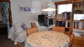 A cozy living room with a sofa, a round table, and a bookshelf filled with books. - The Le Panorama building is located on the 1800 level of the Collons resort. Ideally located, it is (Thyon-Les Collons)