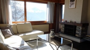 A cozy living room with a sofa, a glass coffee table, and a fireplace. - Beautiful renovated apartment for rent in les Collons (Thyon-Les Collons)