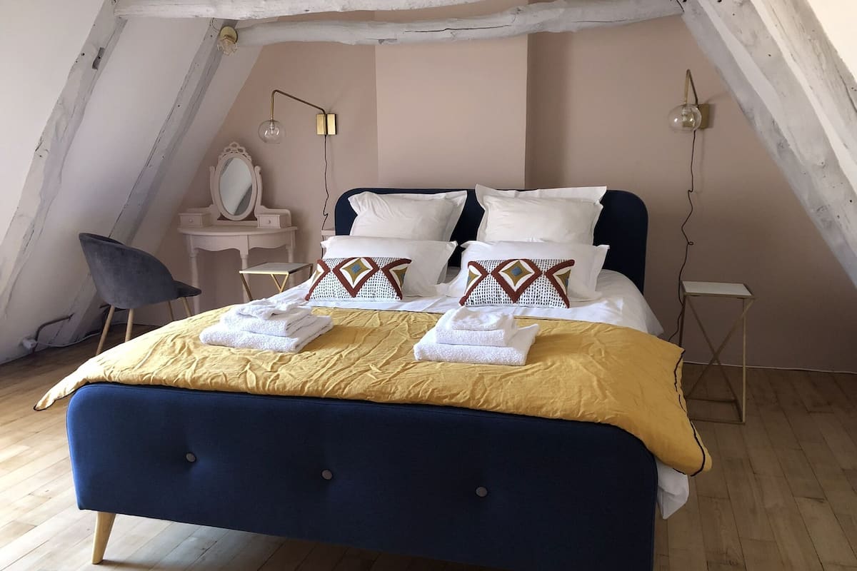 Ein Schlafzimmer mit Bett, Nachttischen, einem Sessel und einem Spiegel.