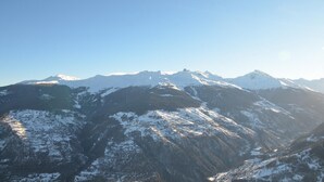 A mountain range with snow-covered peaks and clear blue sky.