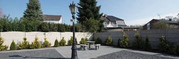 Un patio empedrado con muro de piedra, farol y banco.