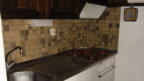 A small kitchen with a sink, stove, and white cabinets. - Nice studio for rent in les Collons (Thyon-Les Collons)