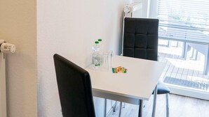 Un espace repas moderne avec une table blanche, des chaises noires et deux œuvres d’art accrochées au mur.