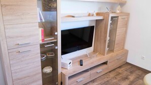 Un salon moderne doté d’un téléviseur encastré, de meubles en bois et d’une vitrine en verre.