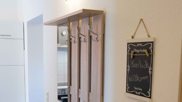 Une cuisine moderne dotée d’un four encastré, d’un banc en bois avec des tiroirs et d’un tableau noir sur lequel sont écrites des notes manuscrites.
