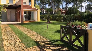 Il s'agit d'une propriété résidentielle dotée d'une allée pavée, d'un petit jardin avec une pelouse et un arbre, ainsi que d'un portail en bois.