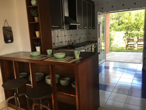 A kitchen with a central island, bar stools, and a view of the outdoor patio area.