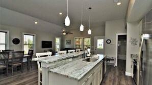 A modern kitchen with a large island, white cabinetry, and a stainless steel refrigerator.