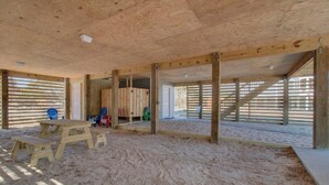 A spacious indoor area with a sandy floor, wooden beams, and a table with benches.