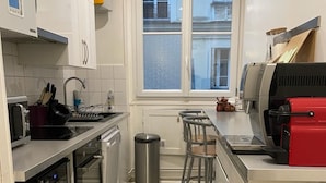 A compact kitchen with a stove, oven, and a small trash bin.