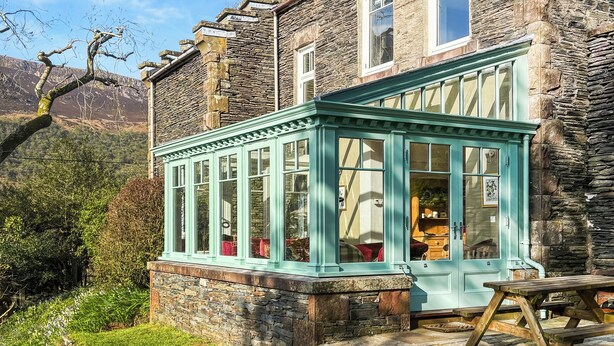 A stone house with a conservatory, a wooden bench, and a stone pathway. - 4 bedroom accommodation in Buttermere, near Keswick (Buttermere, near Keswick)