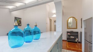 A kitchen with marble countertops, a refrigerator, and a bookshelf. - Pratello Elegante e Raffinata Mansarda (Bologna)