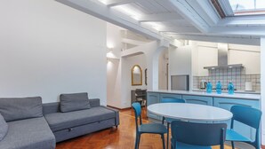 A modern living room with a grey sofa, blue chairs, and a wooden herringbone floor. - Pratello Elegante e Raffinata Mansarda (Bologna)