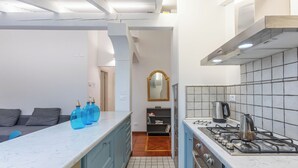 A modern kitchen with blue cabinets, a marble countertop, and a gas stove. - Pratello Elegante e Raffinata Mansarda (Bologna)