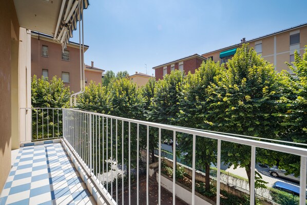 A balcony with a checkered floor, white railing, and views of neighboring buildings and trees. - Sant'Orsola Colorful Huge Apartment (Bologna)