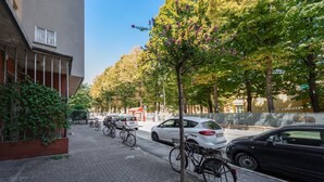 A paved sidewalk with parked bicycles and cars, a building with a balcony, and trees lining the street. - Sant'Orsola Colorful Huge Apartment (Bologna)