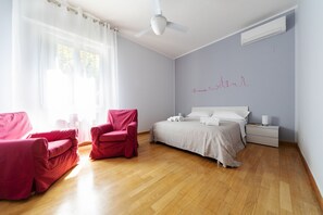 A bedroom with a bed, a nightstand, a chair, and a ceiling fan. - Sant'Orsola Colorful Huge Apartment (Bologna)