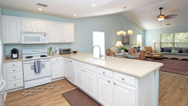 A spacious kitchen with white cabinets, a large island, and a dining area with a chandelier. - TB 62C Updated 3 Bedroom 2 Bath Condo in True Blue Golf Community (Pawleys Island)