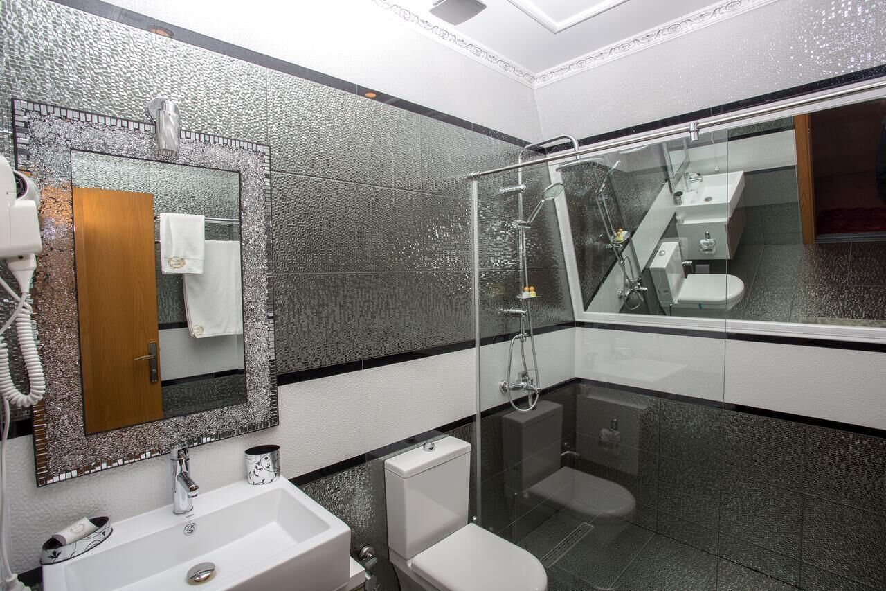 A modern bathroom with a glass-enclosed shower, a large mirror, and a white sink.