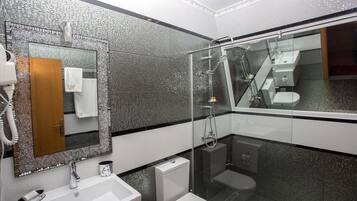 A modern bathroom with a glass-enclosed shower, a large mirror, and a white sink.