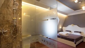 Une chambre d’hôtel moderne dotée d’une douche en verre, d’un lit avec une tête de lit et d’une table de chevet.