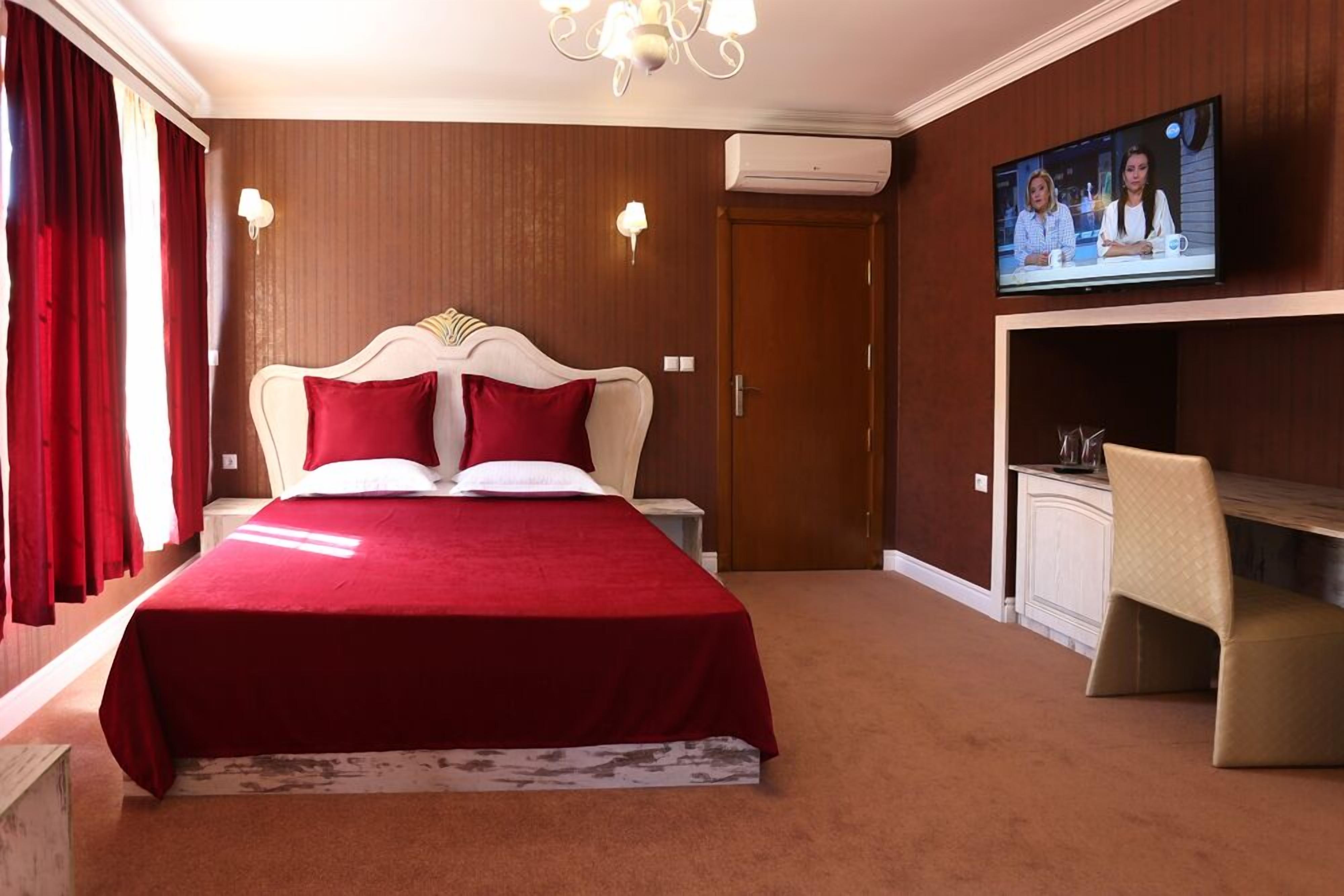 Una habitación de hotel con una cama grande, un televisor en la pared y un escritorio con una silla.