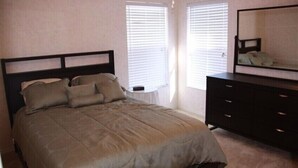 A bedroom with a bed, a dresser, and a mirror.