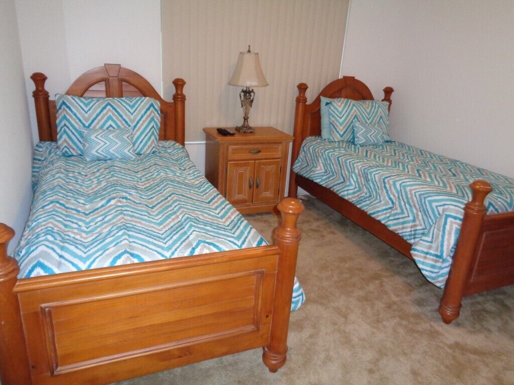 A room with two wooden beds, each with a matching headboard and footboard, and a nightstand with a lamp between them.