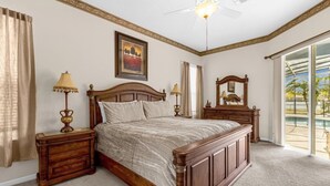 Una camera da letto con un letto grande, due comodini, una ventola a soffitto, un quadro e vista sull'esterno.