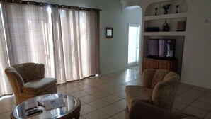 A living room with two armchairs, a glass coffee table, and a television. - Gb1616 (Clermont)