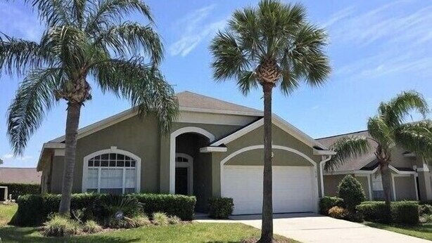 A single-story house with a garage, surrounded by palm trees and well-maintained landscaping. - Gb1616 (Clermont)