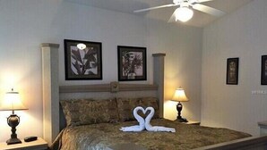 A hotel room with a bed, two wall-mounted lamps, and framed artwork above the bed. - Gb1616 (Clermont)