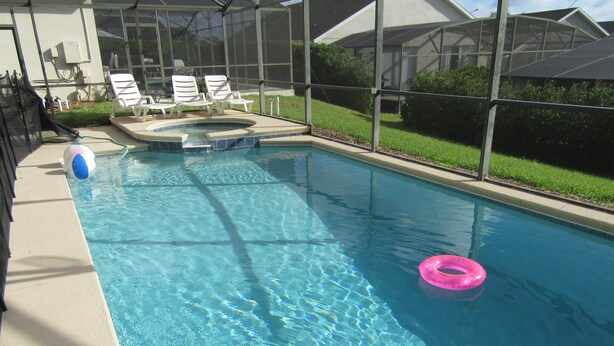 Una piscina con agua cristalina, un jacuzzi y sillas de descanso.