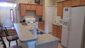 Una cocina con armarios de madera, estufa blanca, un lavabo y un refrigerador.