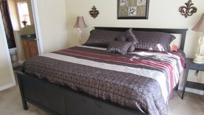 Un dormitorio con una cama grande, una mesita de noche, una lámpara y un espejo.