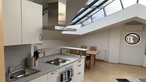 Een moderne keuken met een dakraam, een eethoek met houten stoelen en een radiator aan de muur.