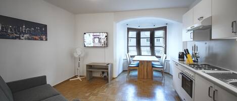 Une cuisine moderne avec un coin repas, un plancher en bois et un tableau représentant un paysage urbain.