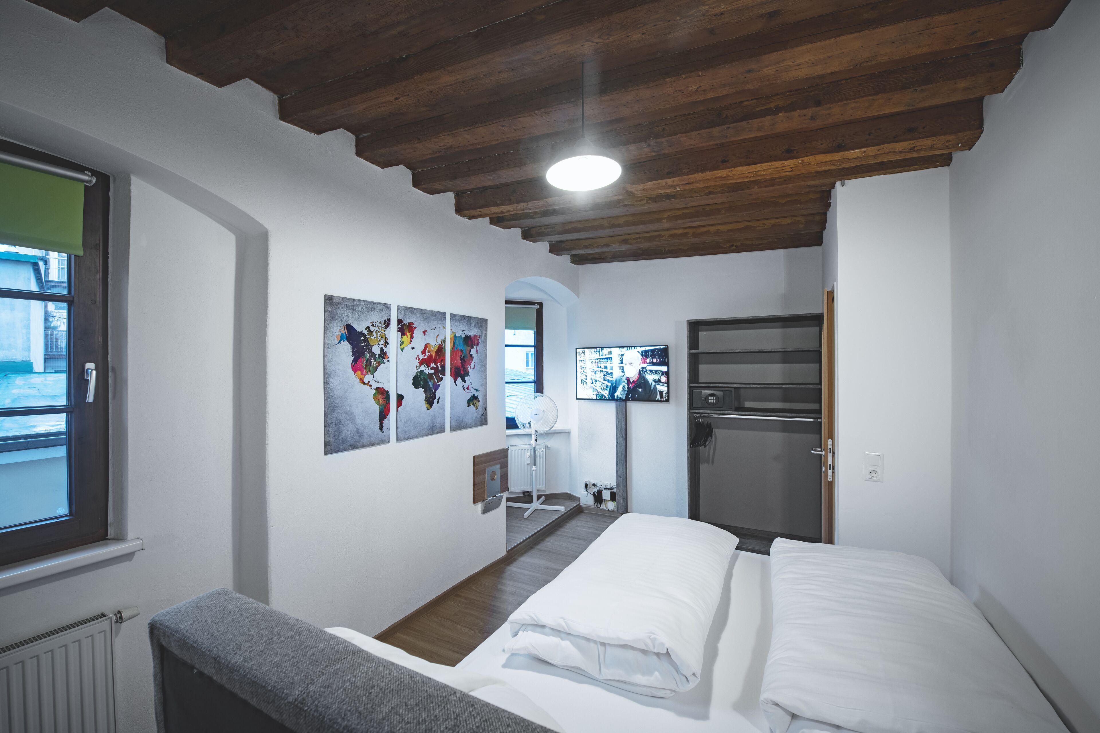 Un dormitorio con techo de madera, una cama, un radiador y obras de arte en la pared.