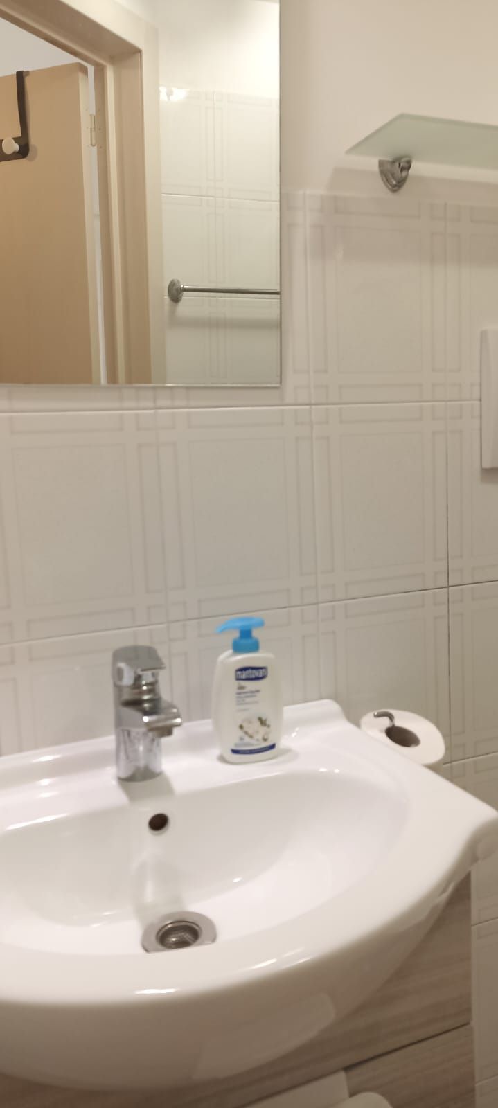A bathroom with a white sink, a mirror, and a towel rack.
