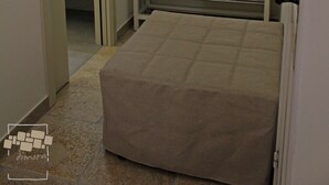 Un dormitorio con cama, espejo y baño visible a través de una puerta abierta.